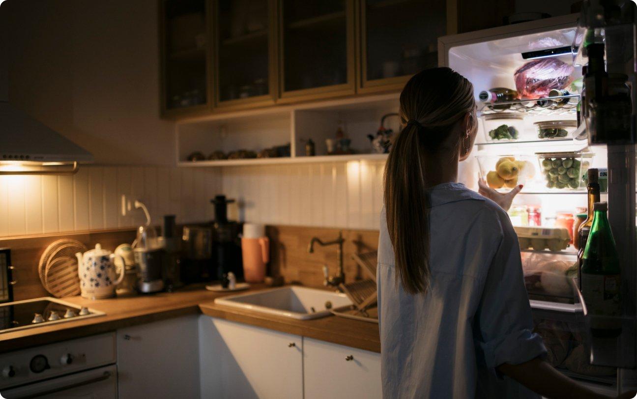 Woman at the kitchen refrigerator looking for a midnight snack