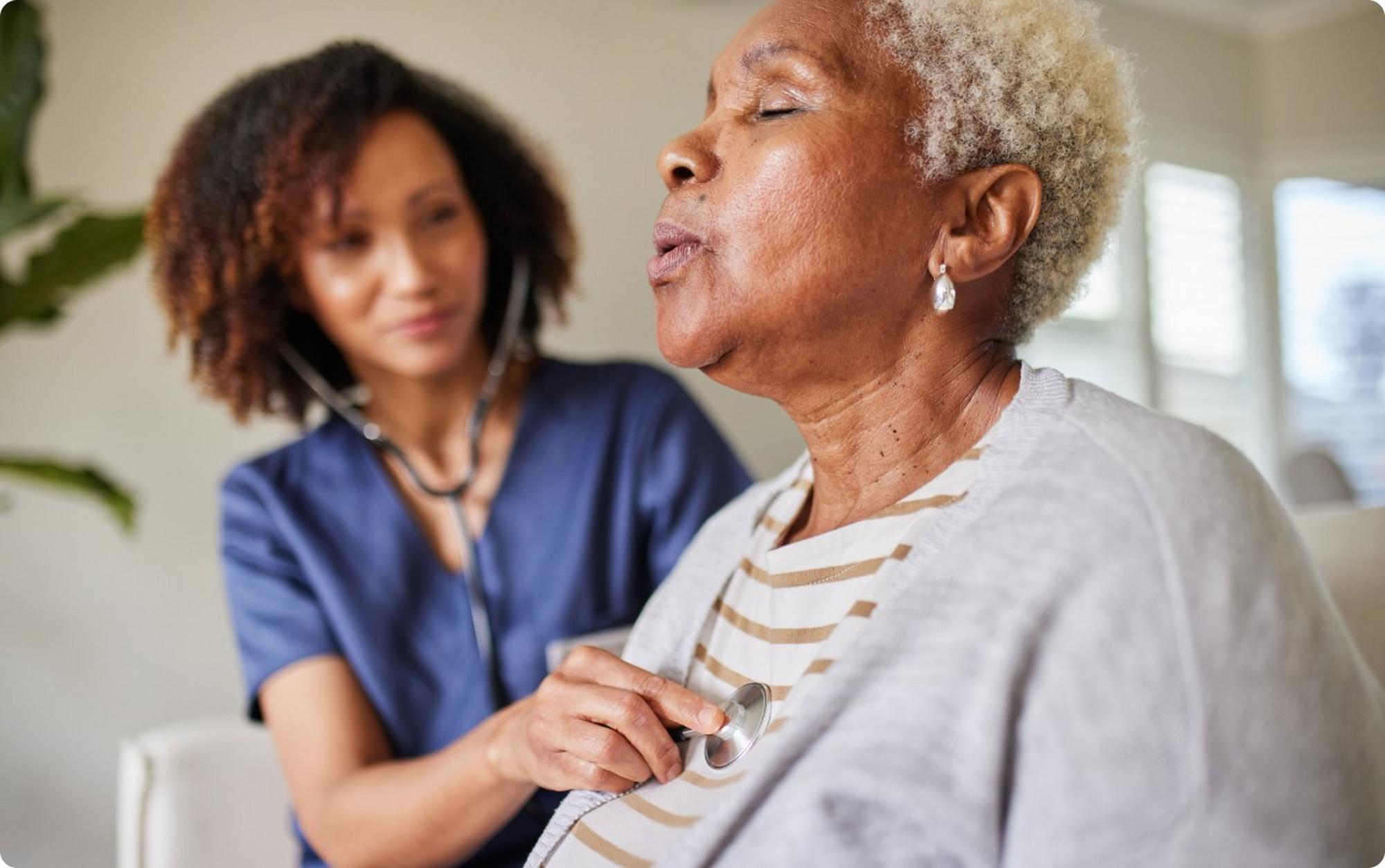 woman taking deep breaths while physician listens to heart