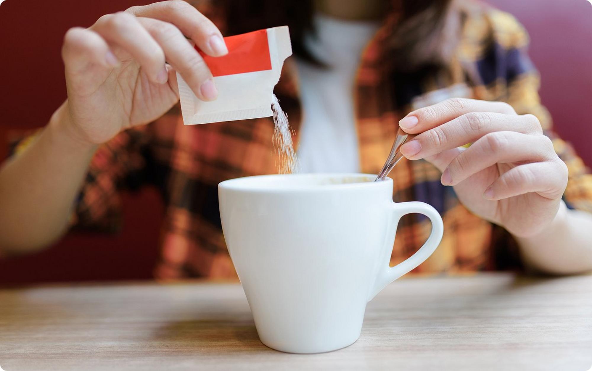person putting sweetener in coffee
