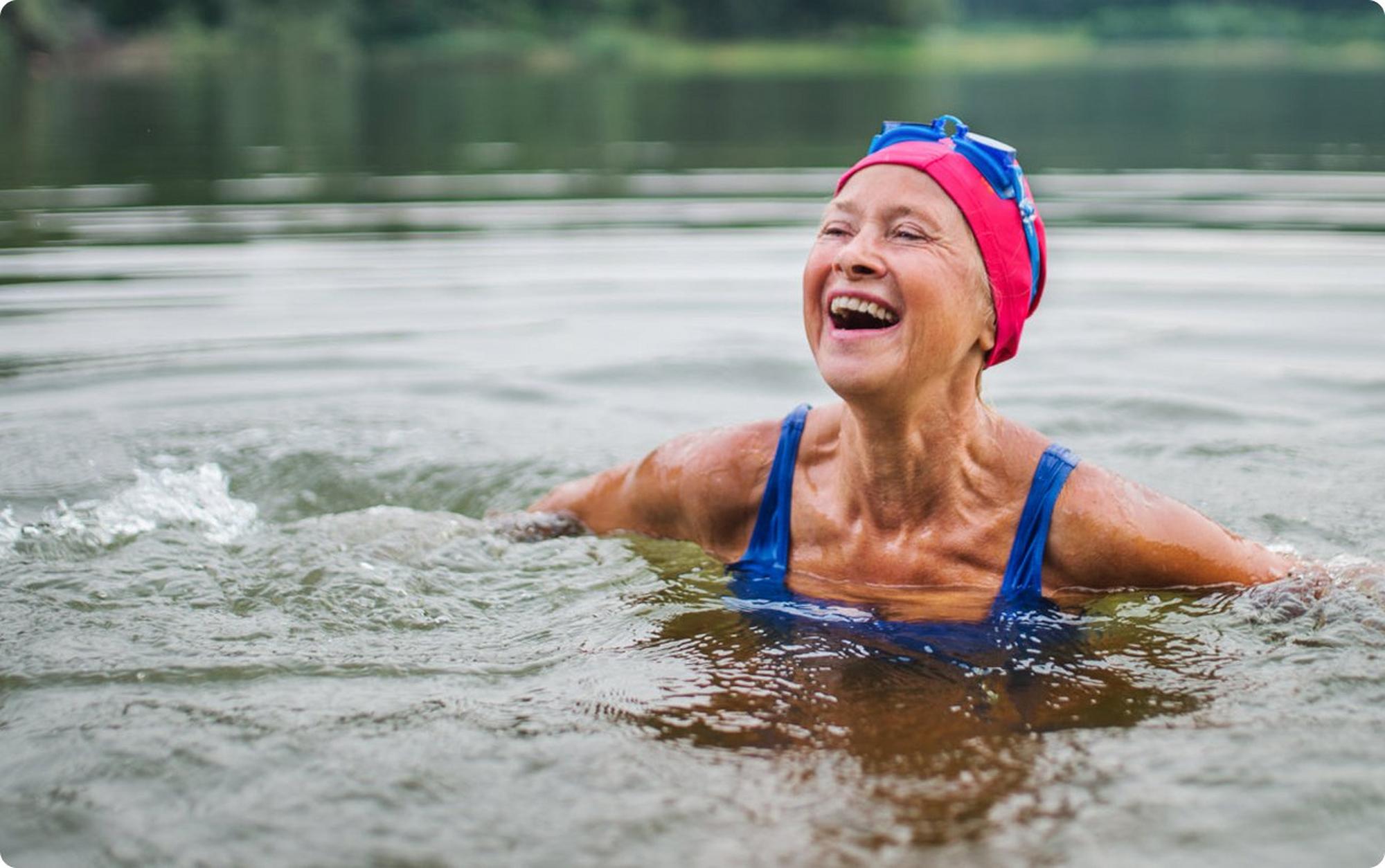 woman in lake swimming wearing swimming cap and goggles
