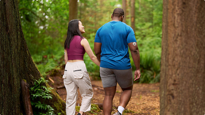 couple walking in the woods, one wearing a Dexcom sensor