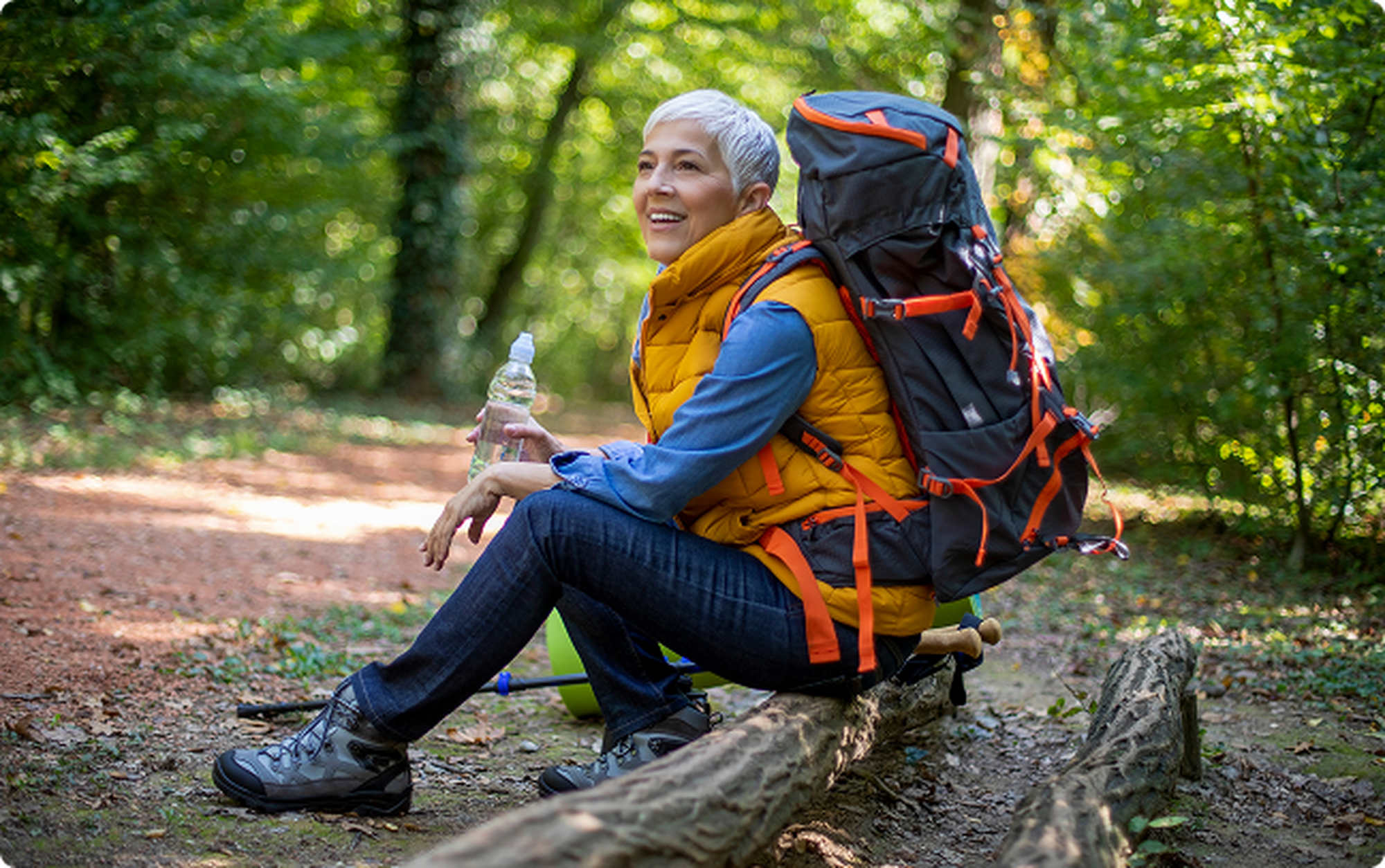hiker stopped on a log while on a trail