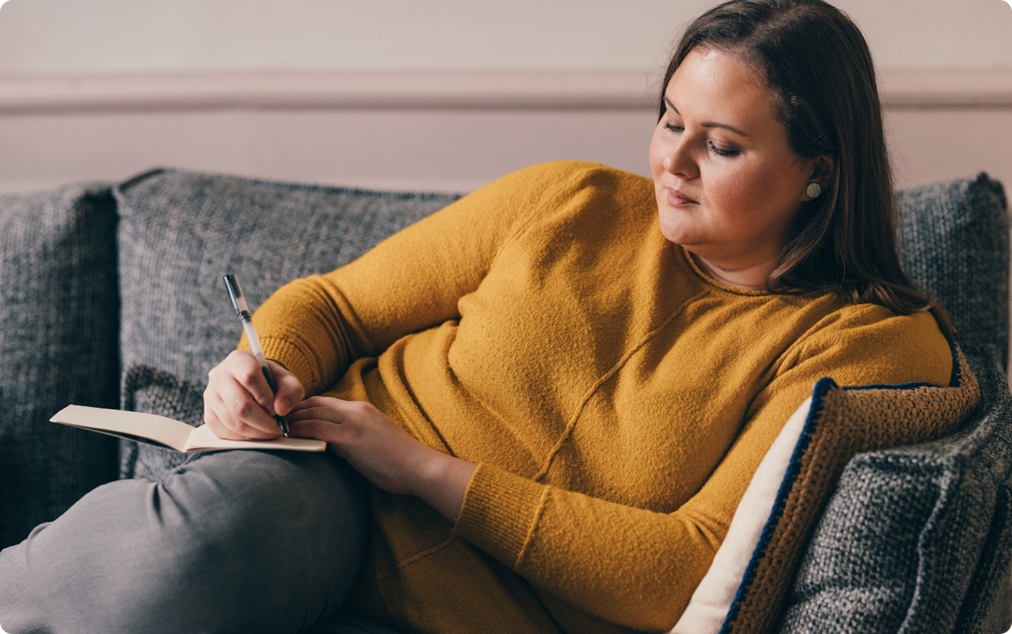 woman taking notes on the couch