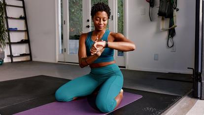 woman working out on mat and looking at watch