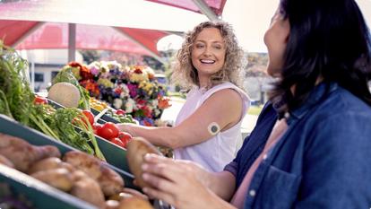 smiling woman wearing Stelo biosensor with friend at farmers market
