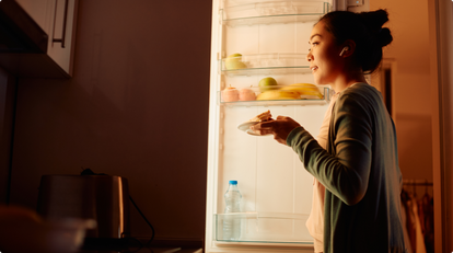 Woman getting food out of the fridge at night