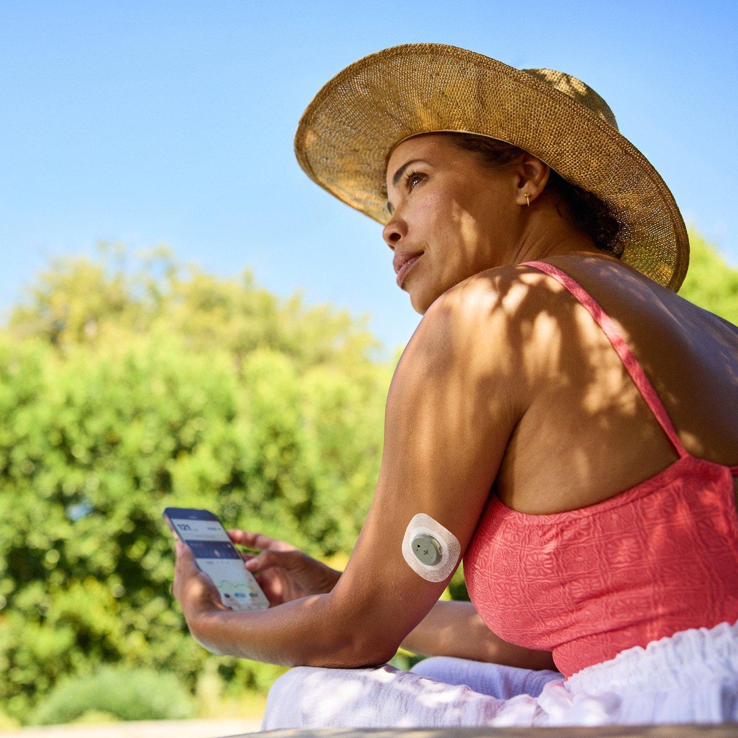 woman wearing stelo and holding smart phone with stelo app