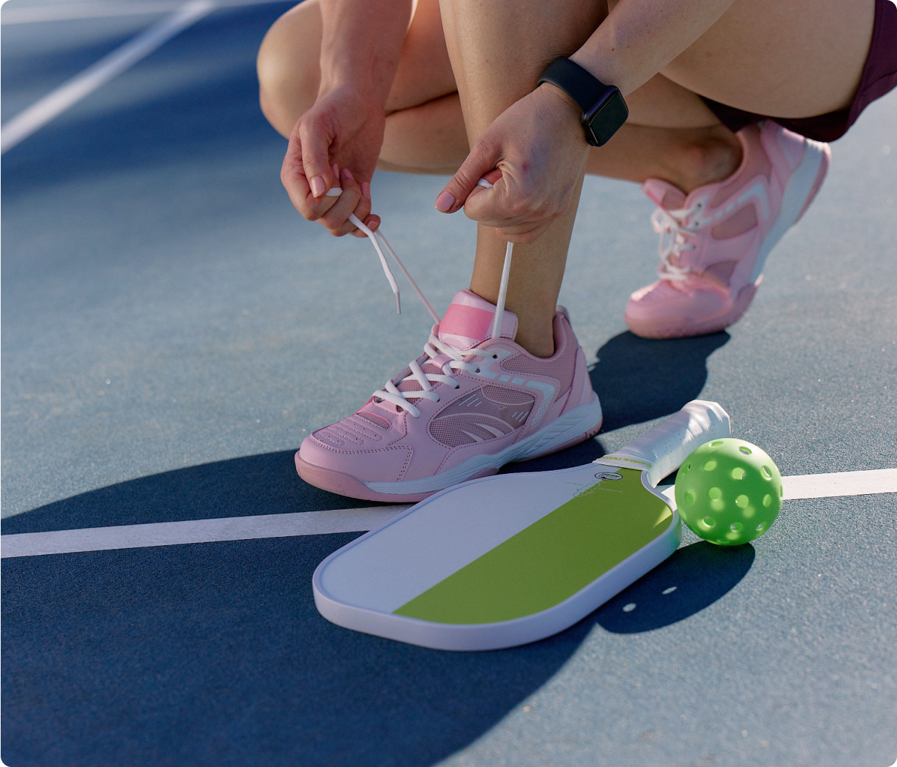 Woman tying tennis shoes on a pickleball court