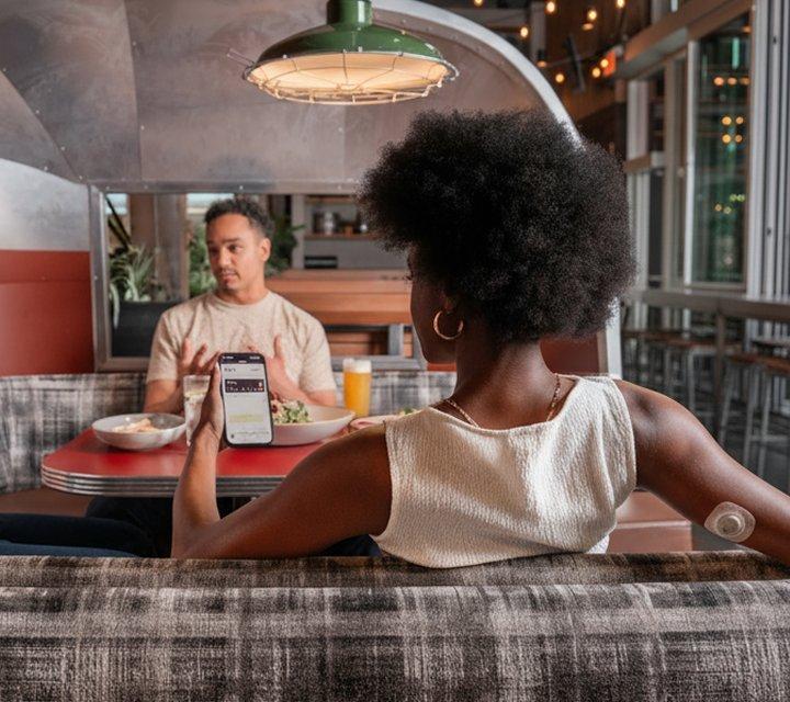 woman wearing stelo biosensor while looking at stelo app on phone