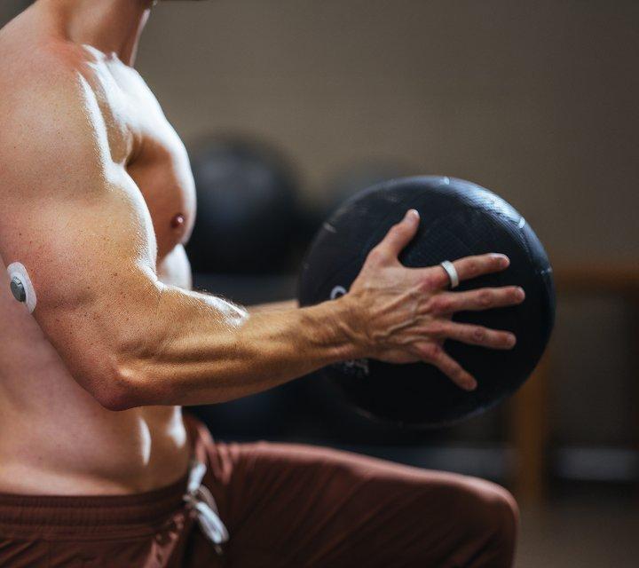 man wearing stelo biosensor while exercising with medicine ball