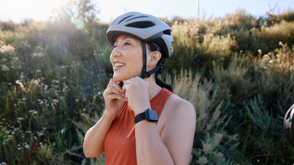 woman putting on helmet for biking