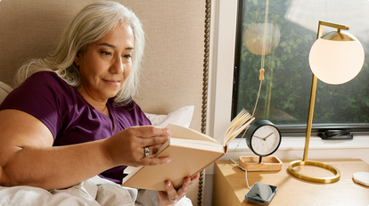 woman reading book in bed