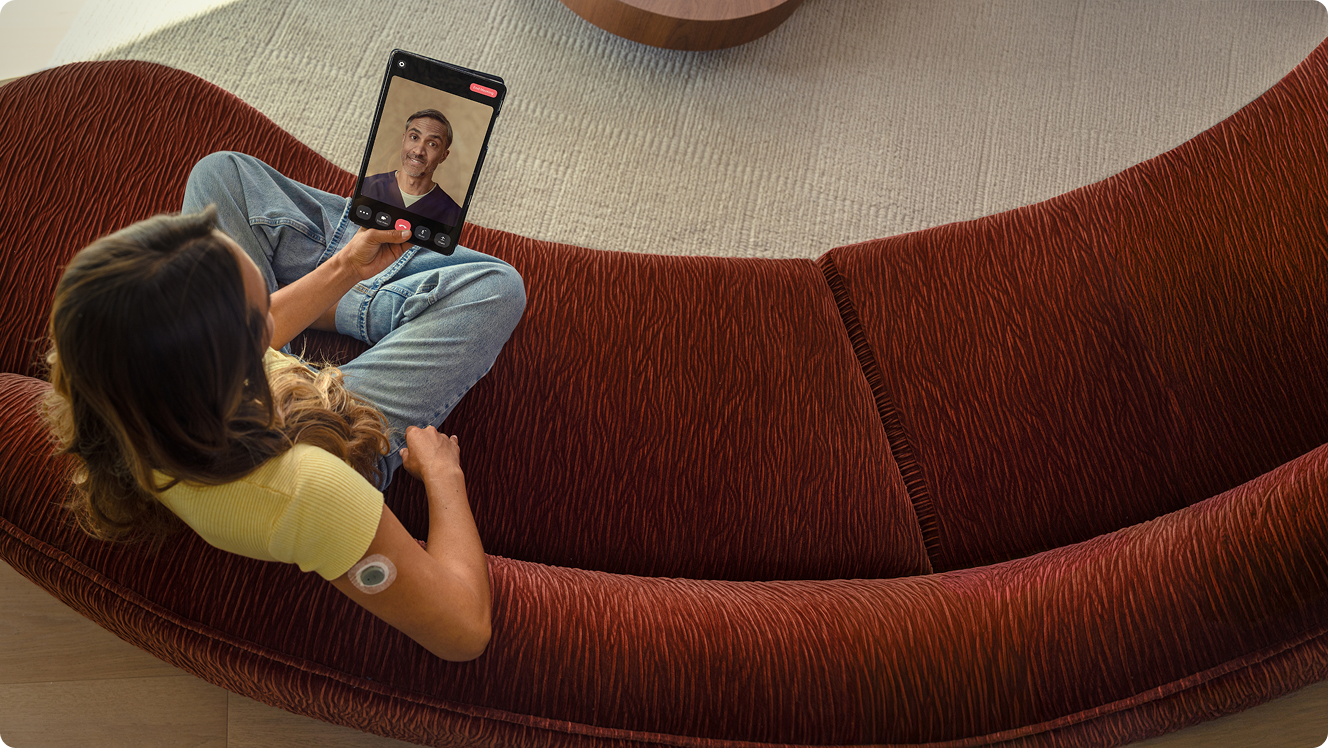 Woman sitting on the couch, attending a video call on her smart device.