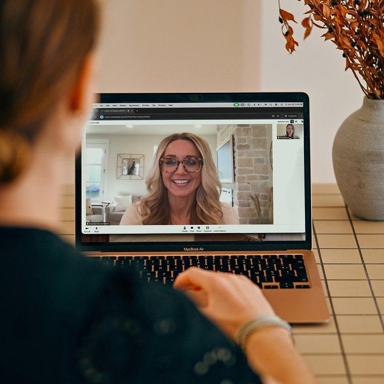 Woman wearing Stelo glucose biosensor on her arm and attending a video call with a nutritionist.