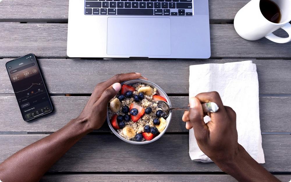 Person eating a fruit and oats bowl at their computer