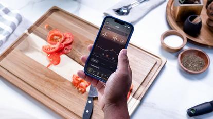 Person holding phone looking at Stelo app while prepping food in kitchen