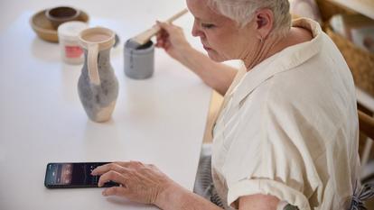 Woman checking her numbers while glazing a pot
