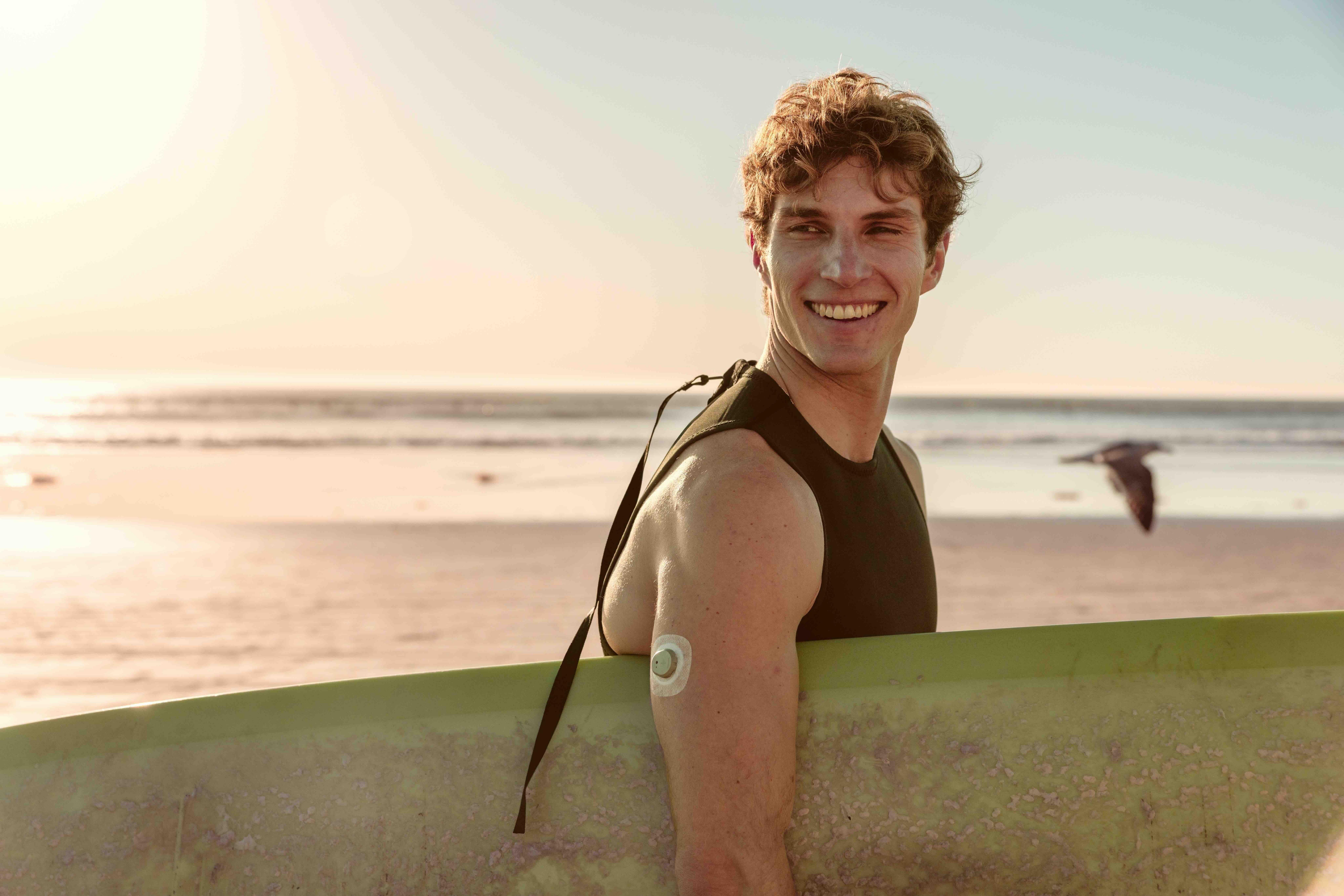 Surfer wearing Stelo carrying surfer under arm