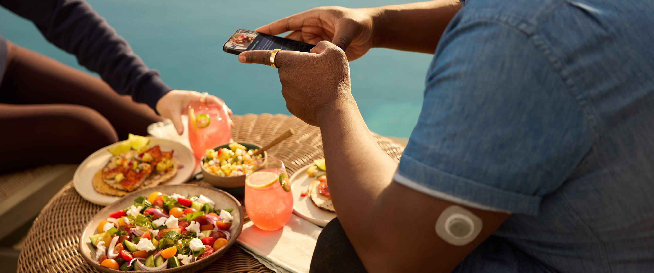 man wearing stelo and oura ring taking a picture of food with smart phone