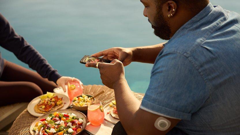 man wearing stelo and oura ring taking a picture of food with smart phone
