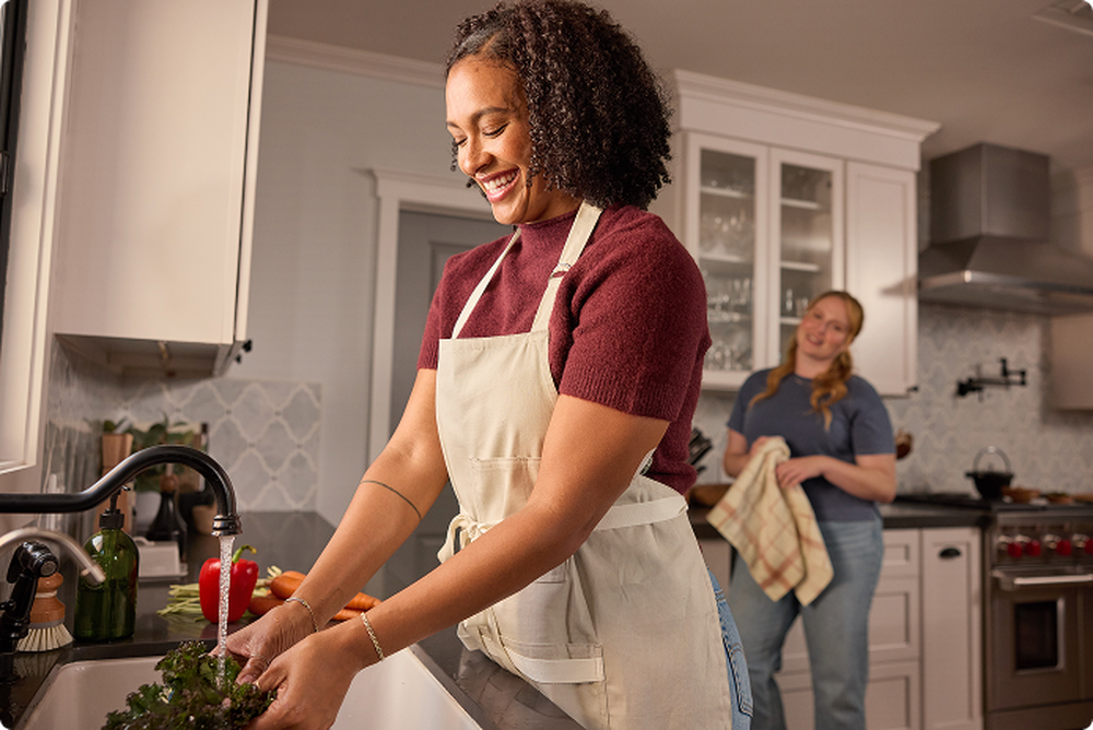 Woman cleaning lettuce with water in the kitchen.