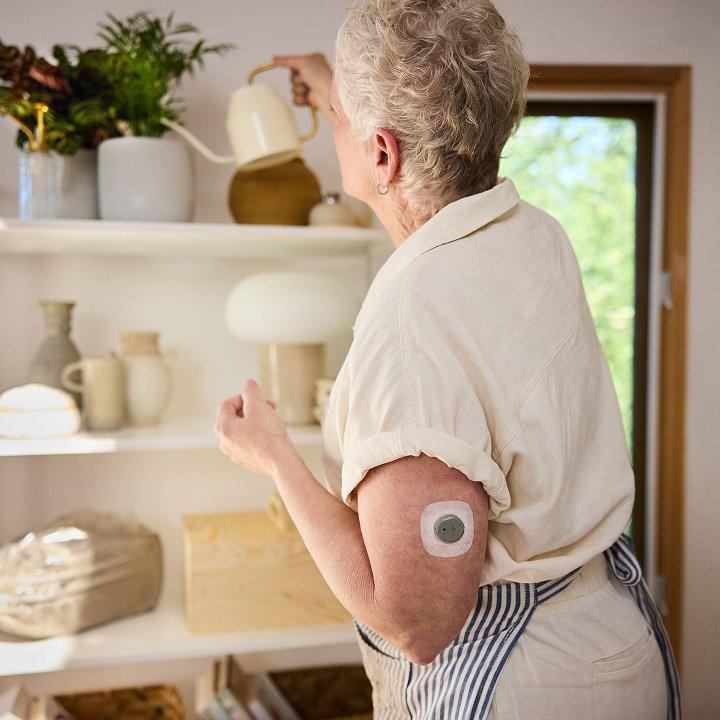 woman watering plant wearing stelo glucose biosensor