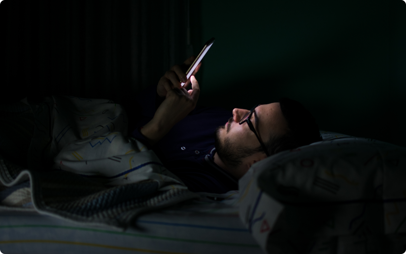 man checking phone in bed