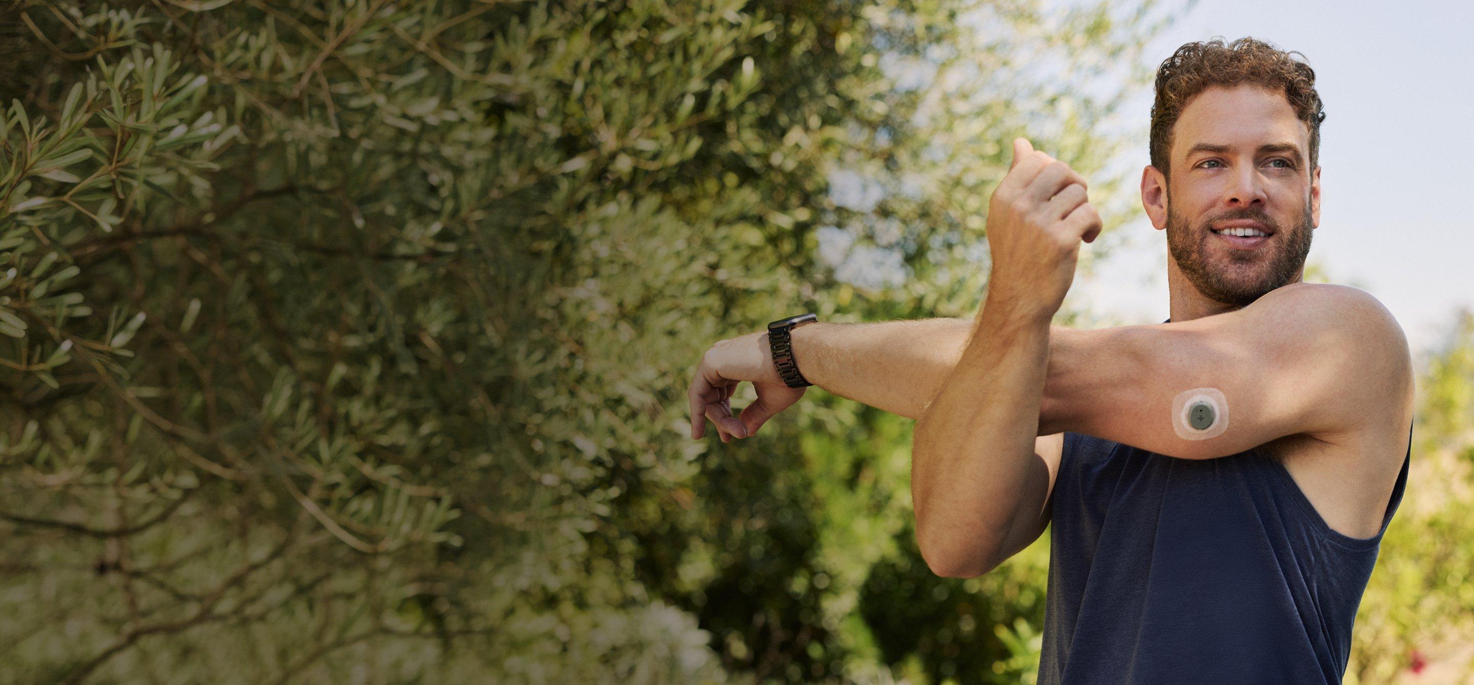 Man stretching outside, wearing Stelo glucose biosensor on the back of his arm