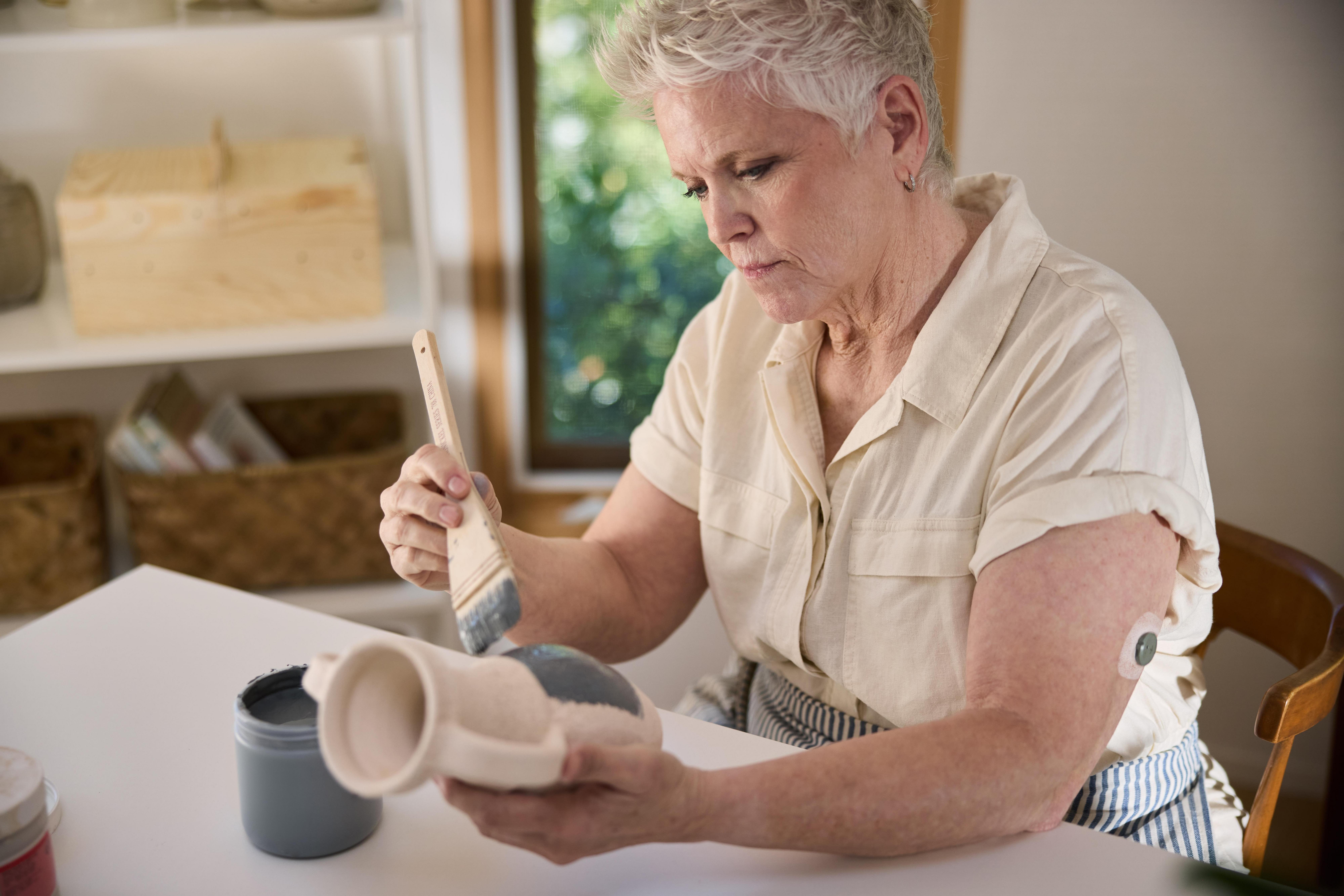 woman wearing stelo while glazing ceramics