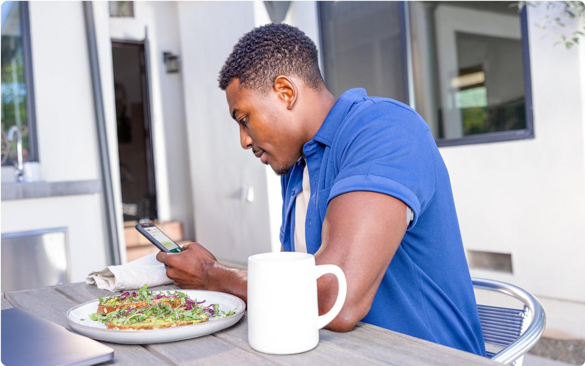 man holding phone eating food