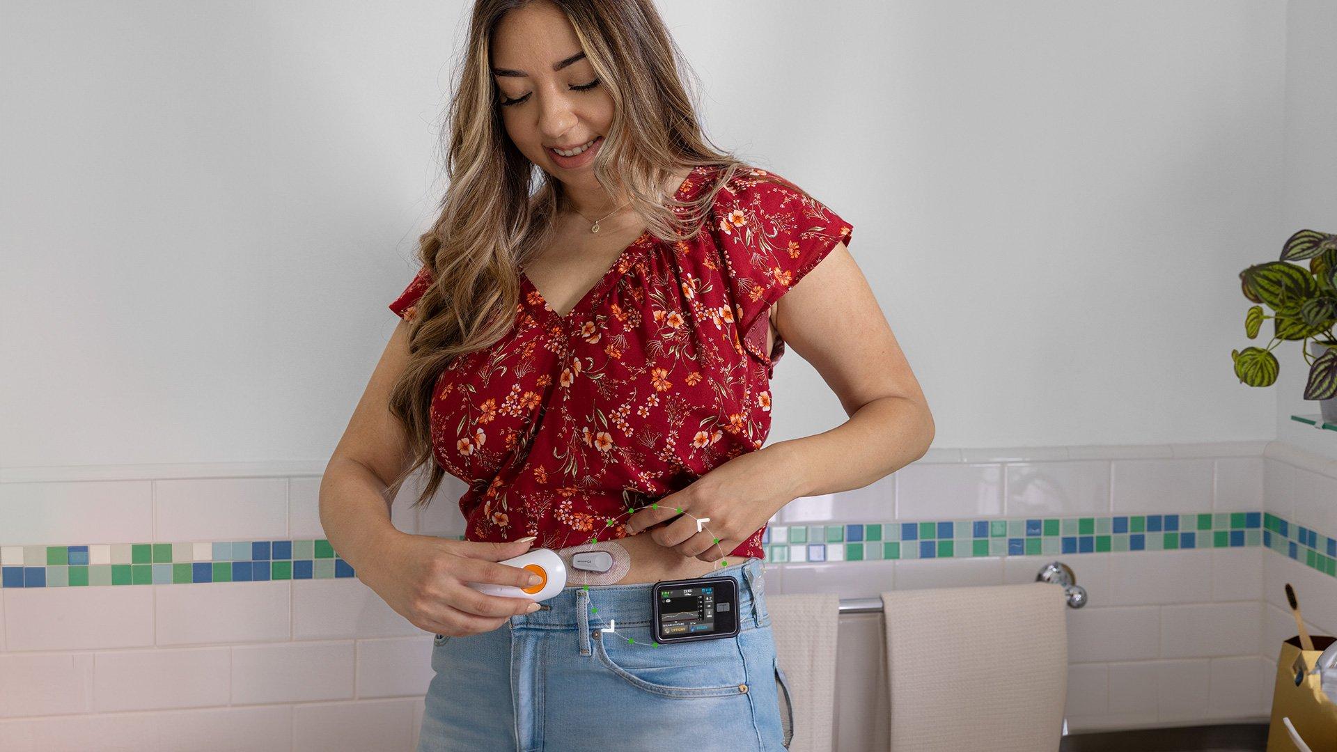 Woman in red shirt attaching Dexcom device to her belly