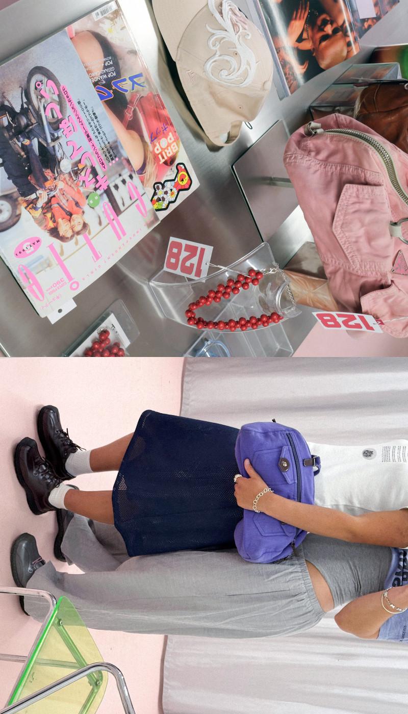 Persoon in zwarte leren veterschoenen met witte sokken, met een paarse tas