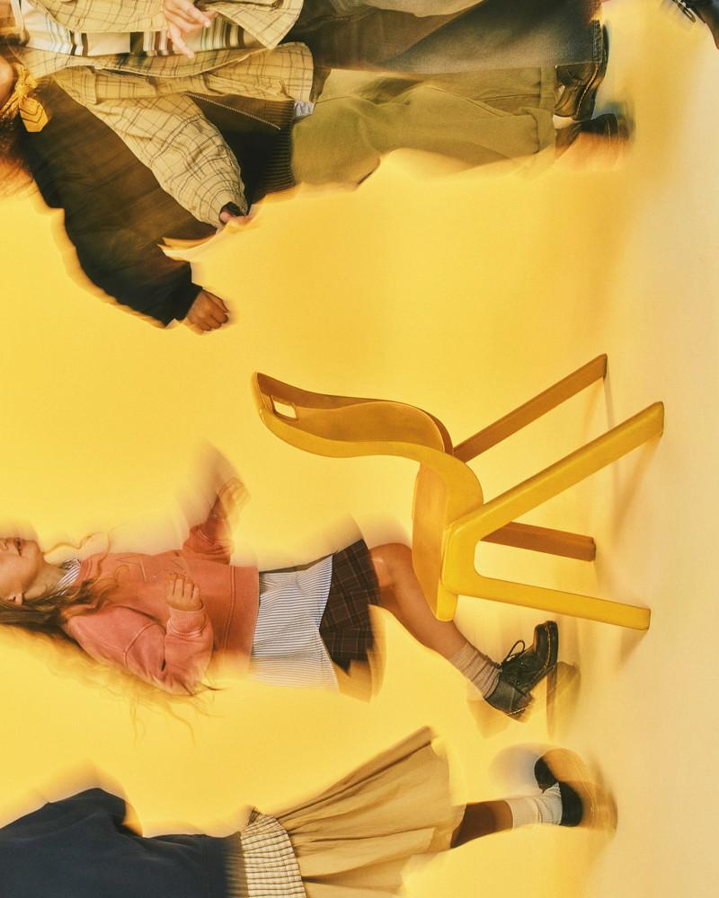 Black leather lace-up shoes with grey socks on a person lying by a tipped yellow chair