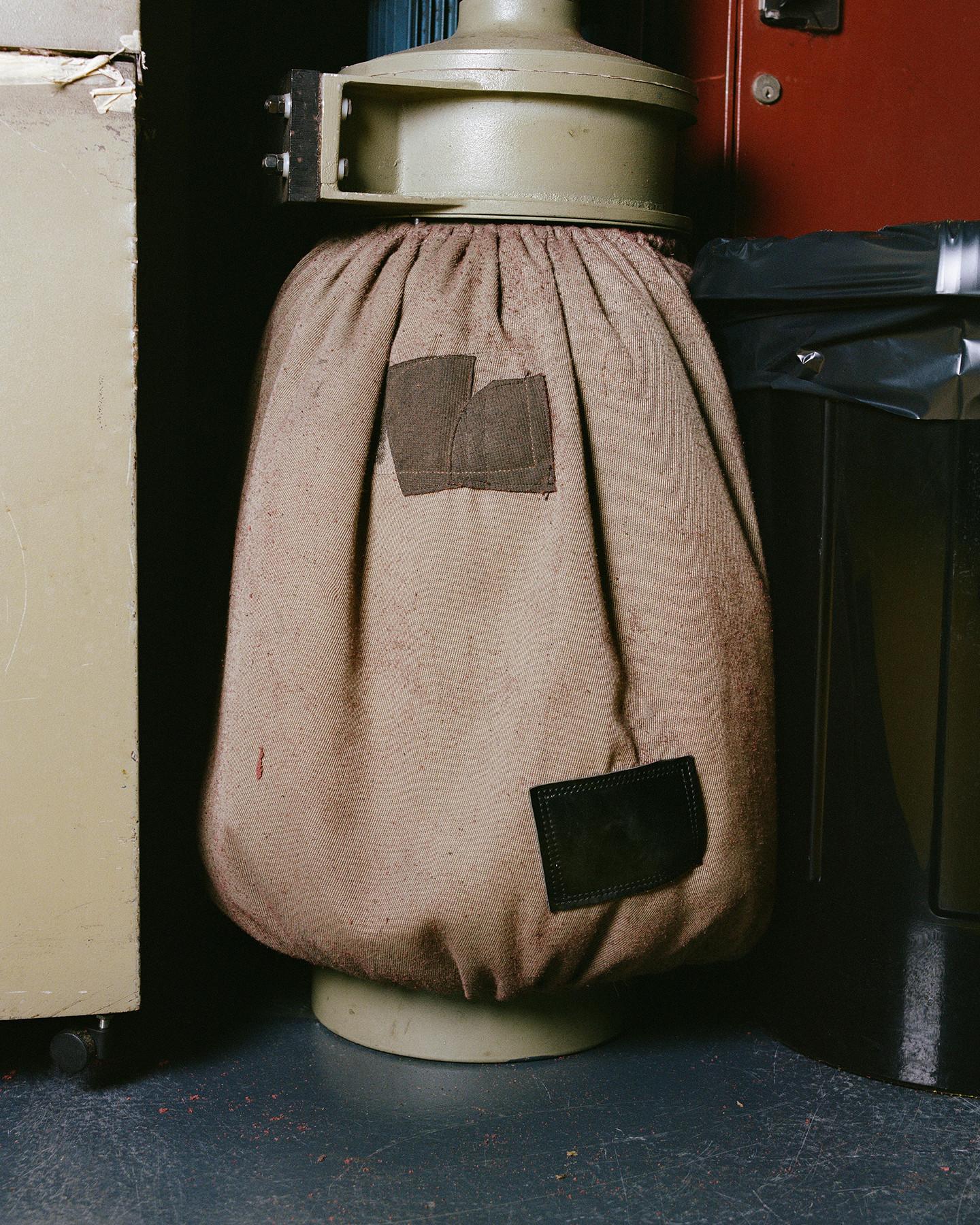 Taupe canvas tas met trekkoord, gestikt patches en een versleten, gespikkelde textuur