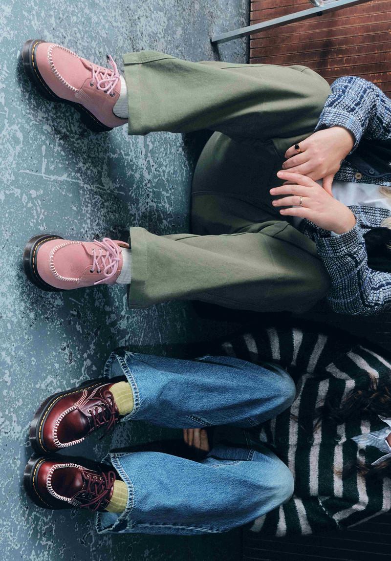 Zwei Personen sitzend, rosa und bordeauxrote Lederschuhe mit Kontrastnaht und gelber Naht