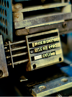 Primer plano de una placa metálica gastada en una máquina industrial, letras en relieve