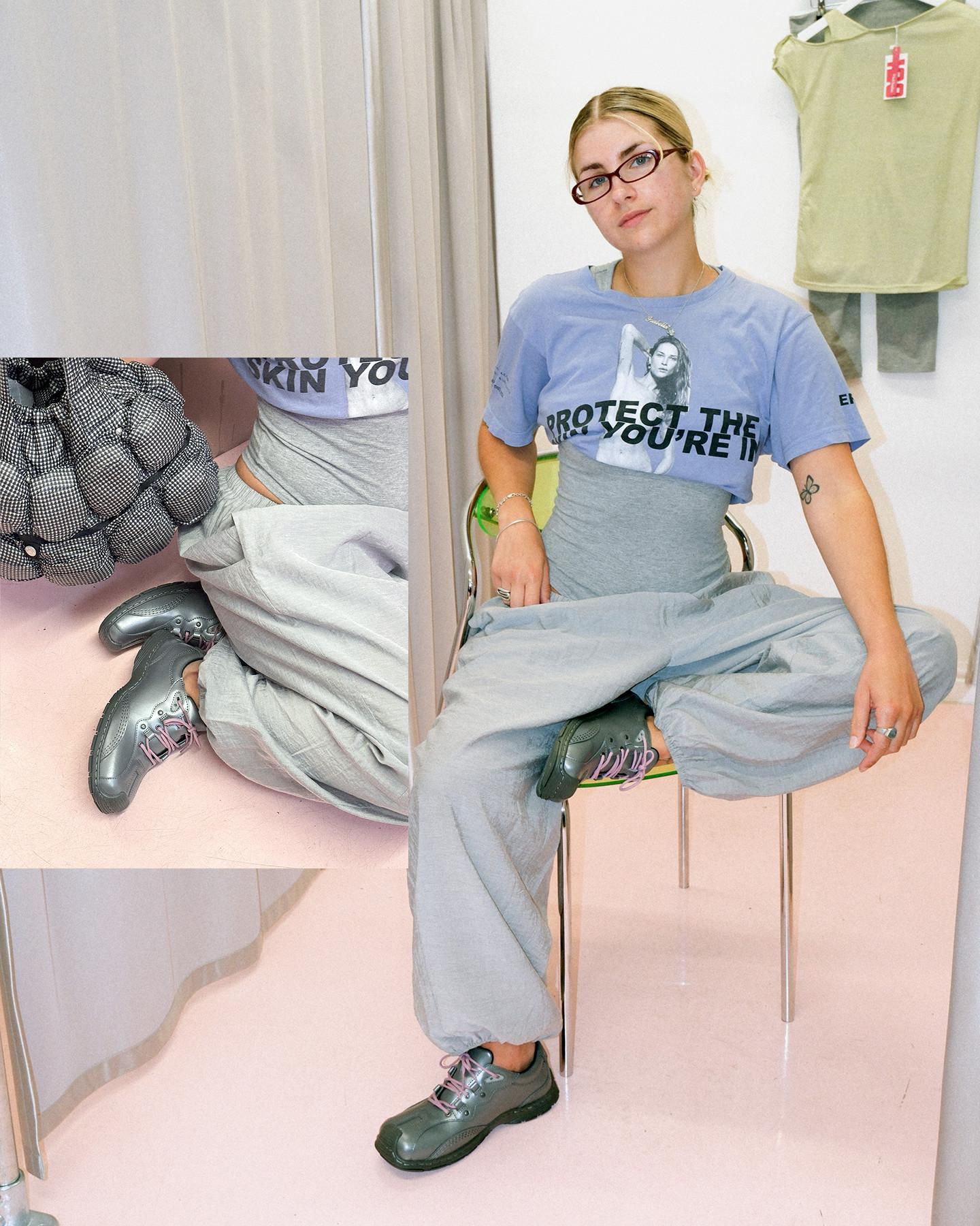 Zittende persoon in grijze Dr. Martens schoenen met roze veters en een broek met wijde pijpen