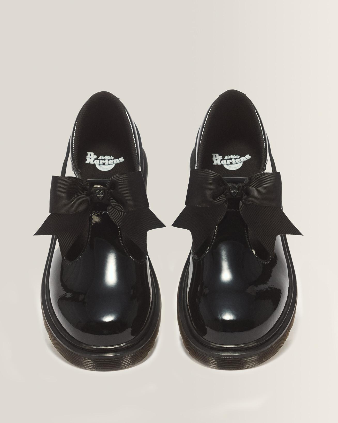 Pair of black patent Mary Jane shoes with satin bows, viewed from above