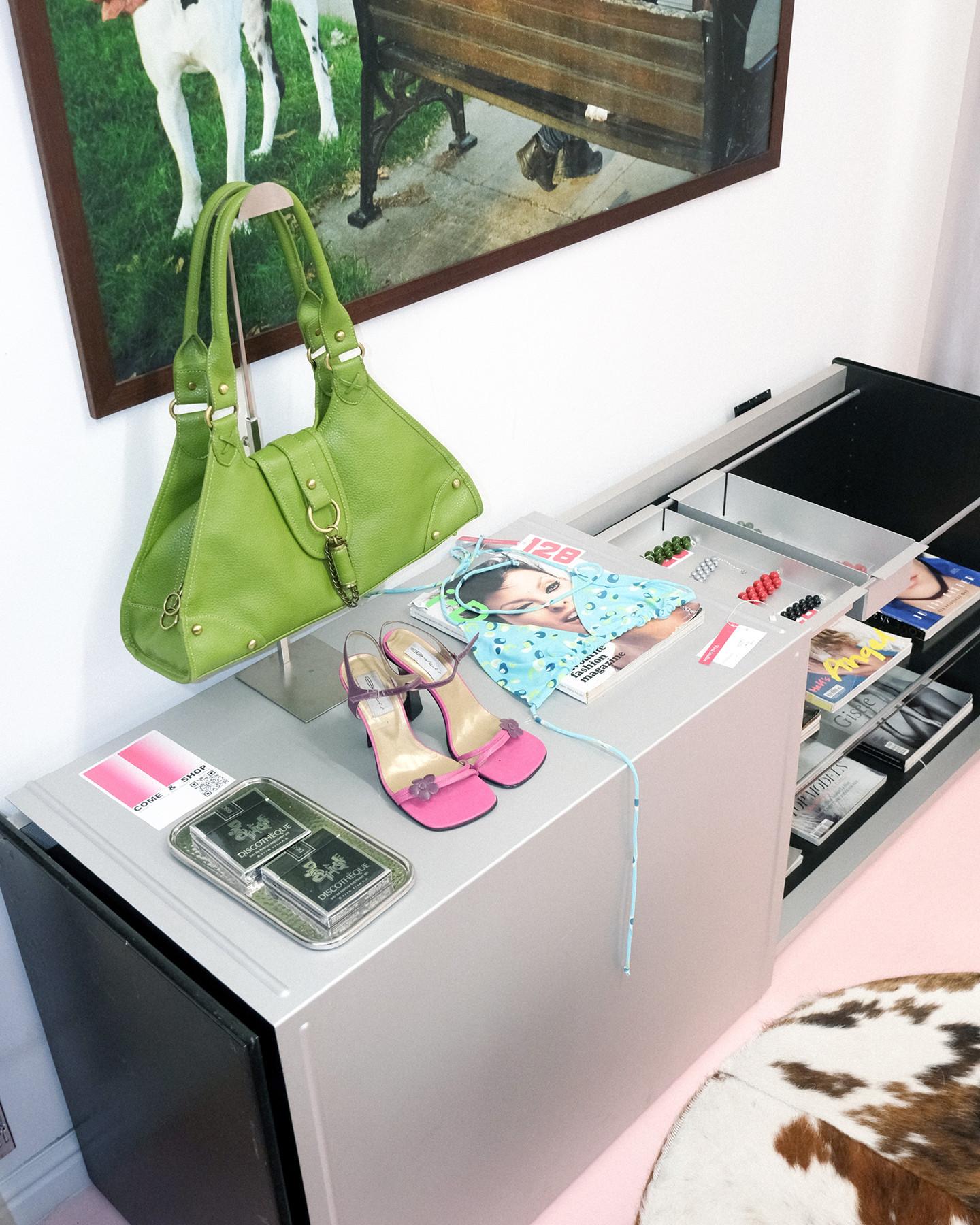 Lime green grained leather shoulder bag with brass hardware, hanging over a metal drawer unit