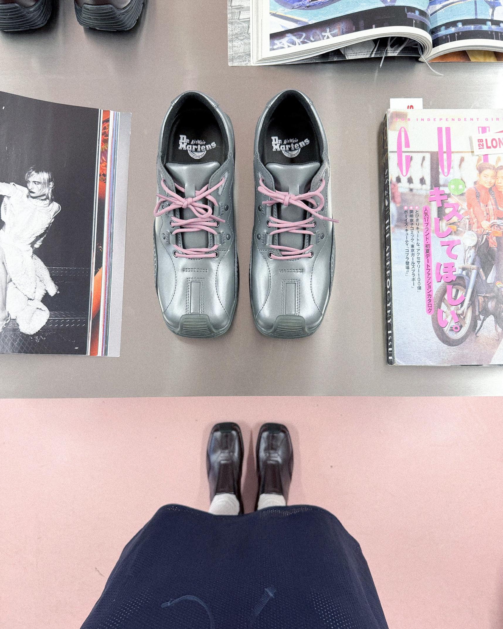 Zwarte Dr. Martens schoenen met roze veters, flat lay tussen tijdschriften