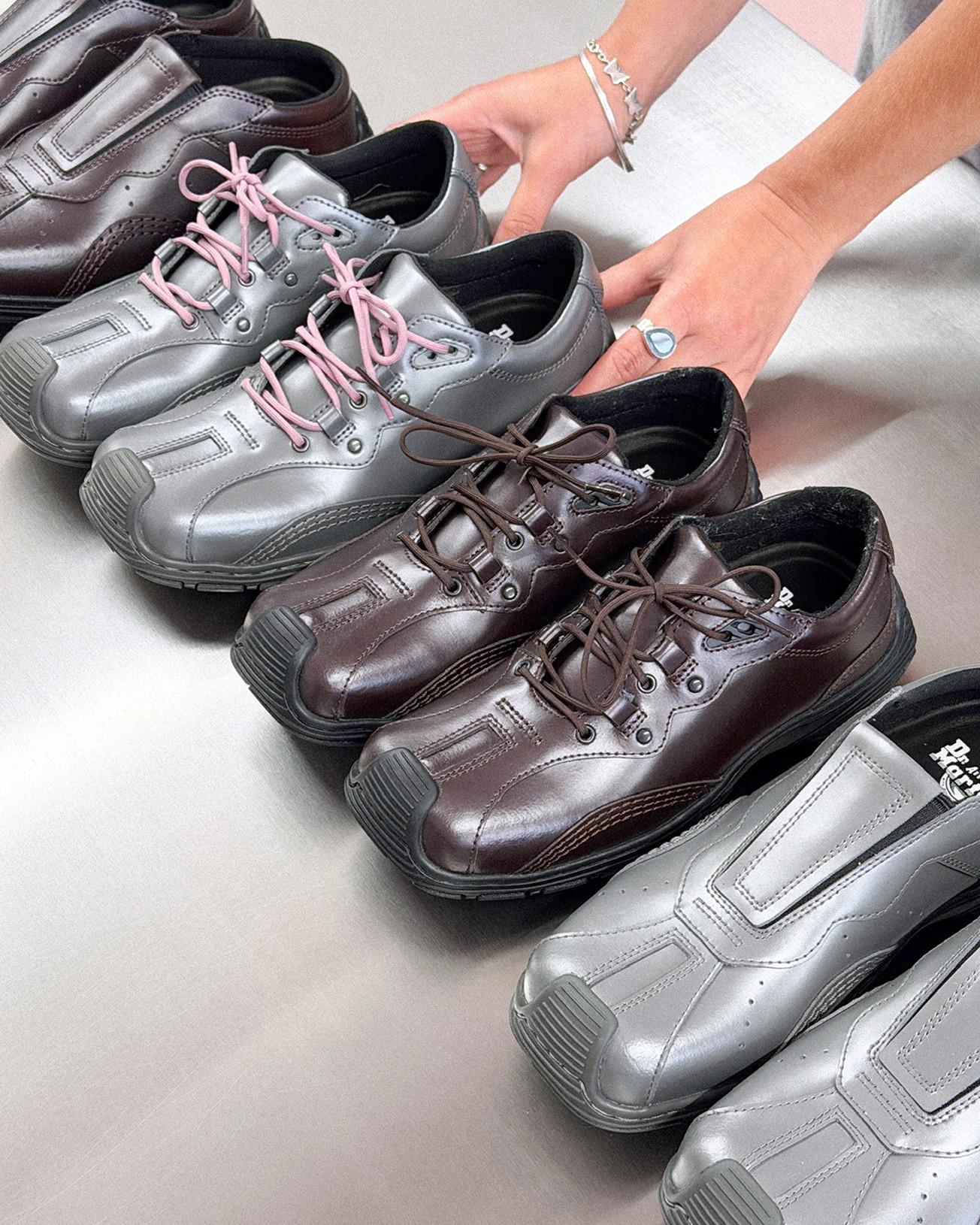 Handen leggen grijze en donkerbruine leren veterschoenen op geborsteld metaal