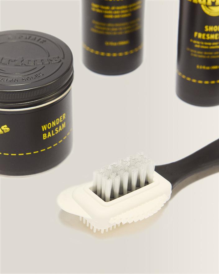 Boîte noire de Wonder Balsam Dr. Martens et brosse à poils blancs sur une surface pâle