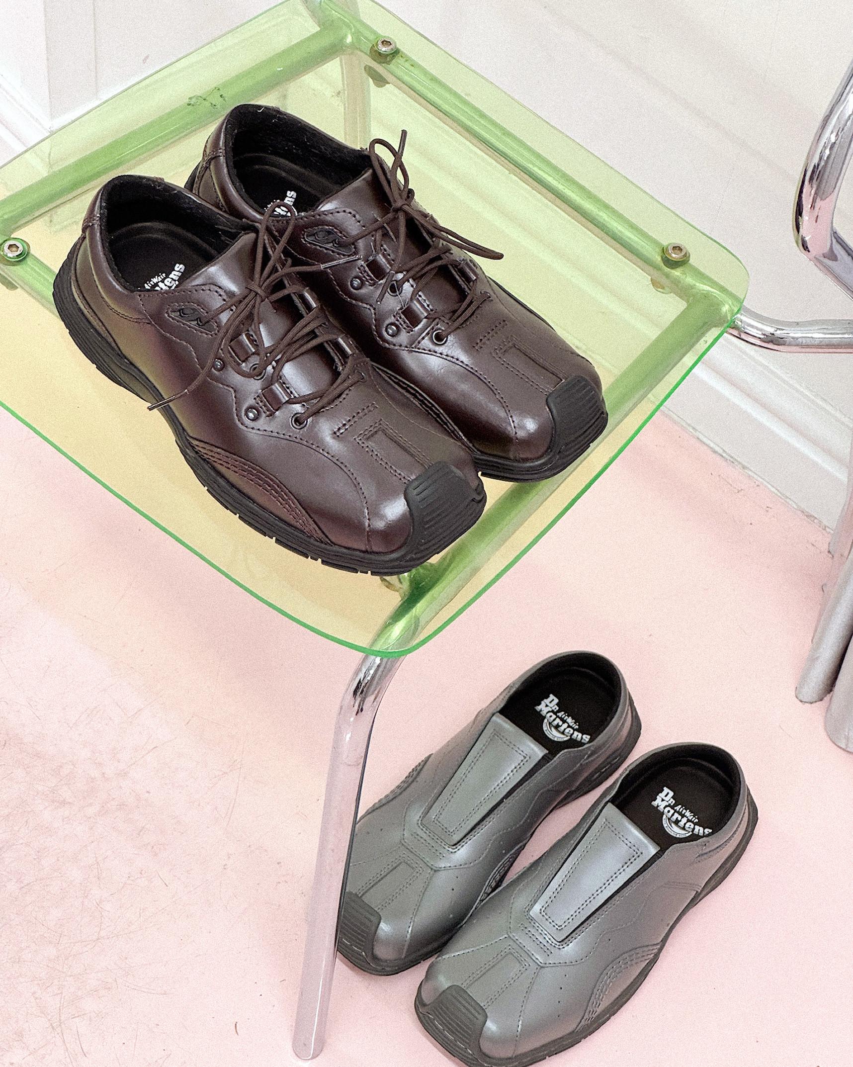 Donkerbruine leren veterschoenen op groen glazen stoel, grijze instappers op roze vloer