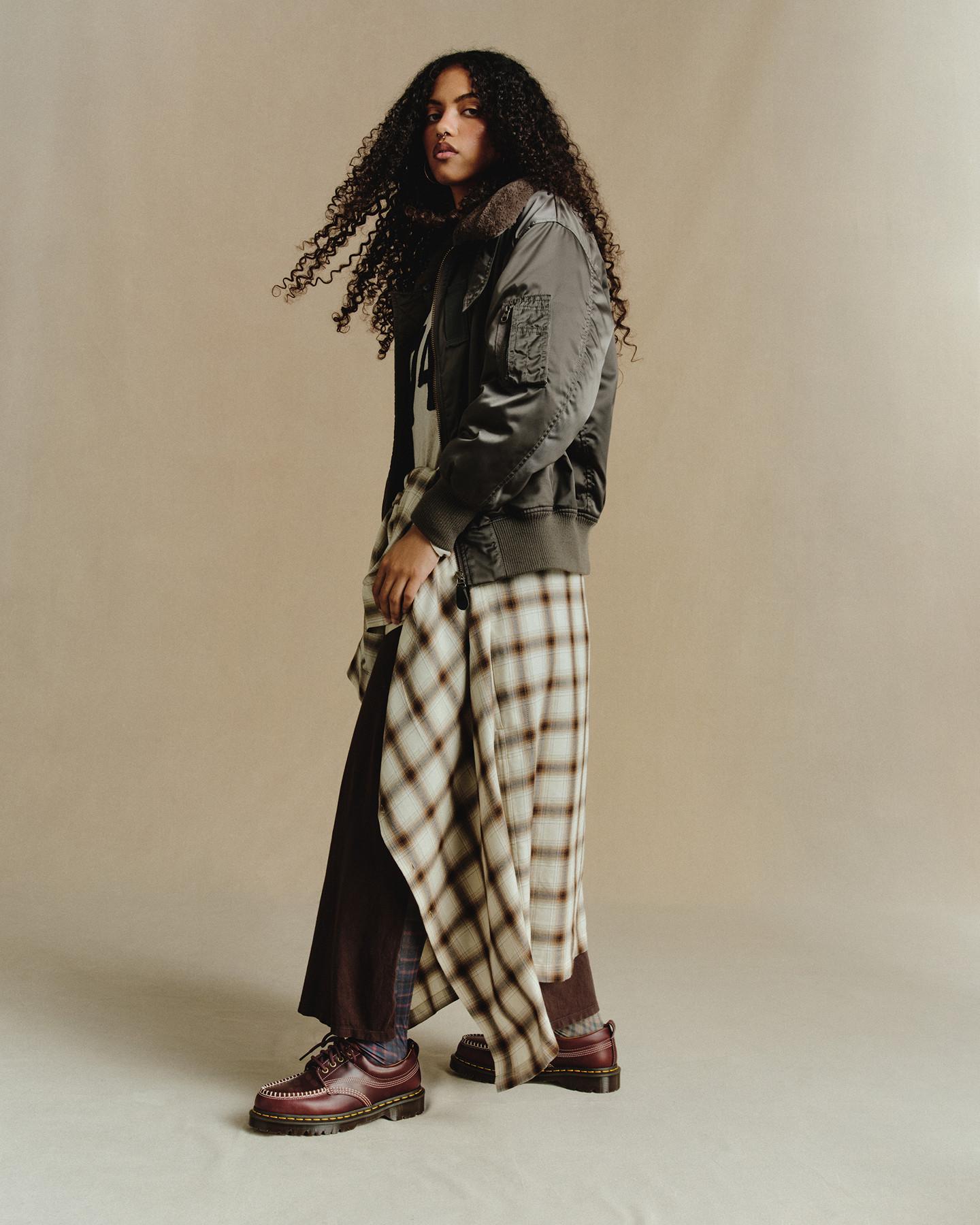 Person in a bomber jacket and wide check trousers, wearing cherry red leather shoes