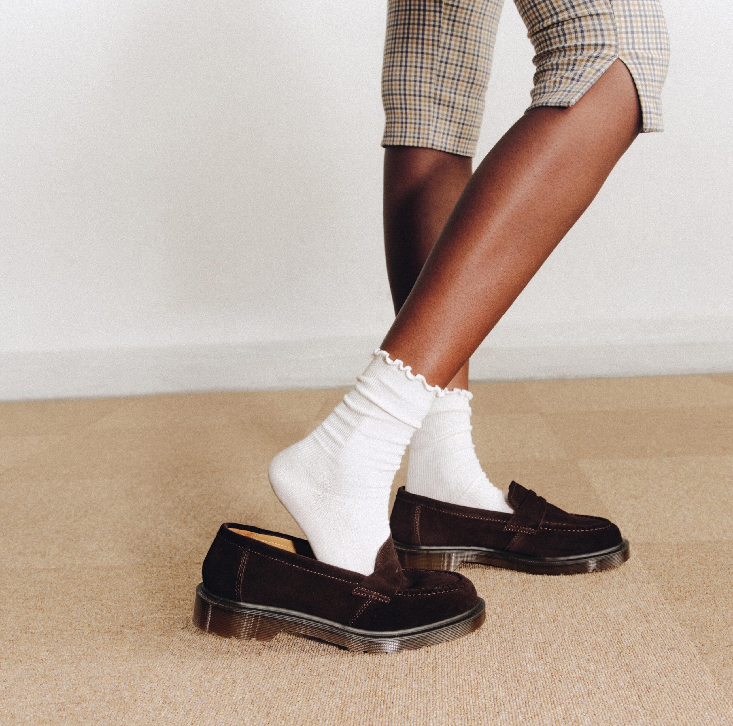 Black suede loafers with tassel detail, worn with white frill socks and checked trousers