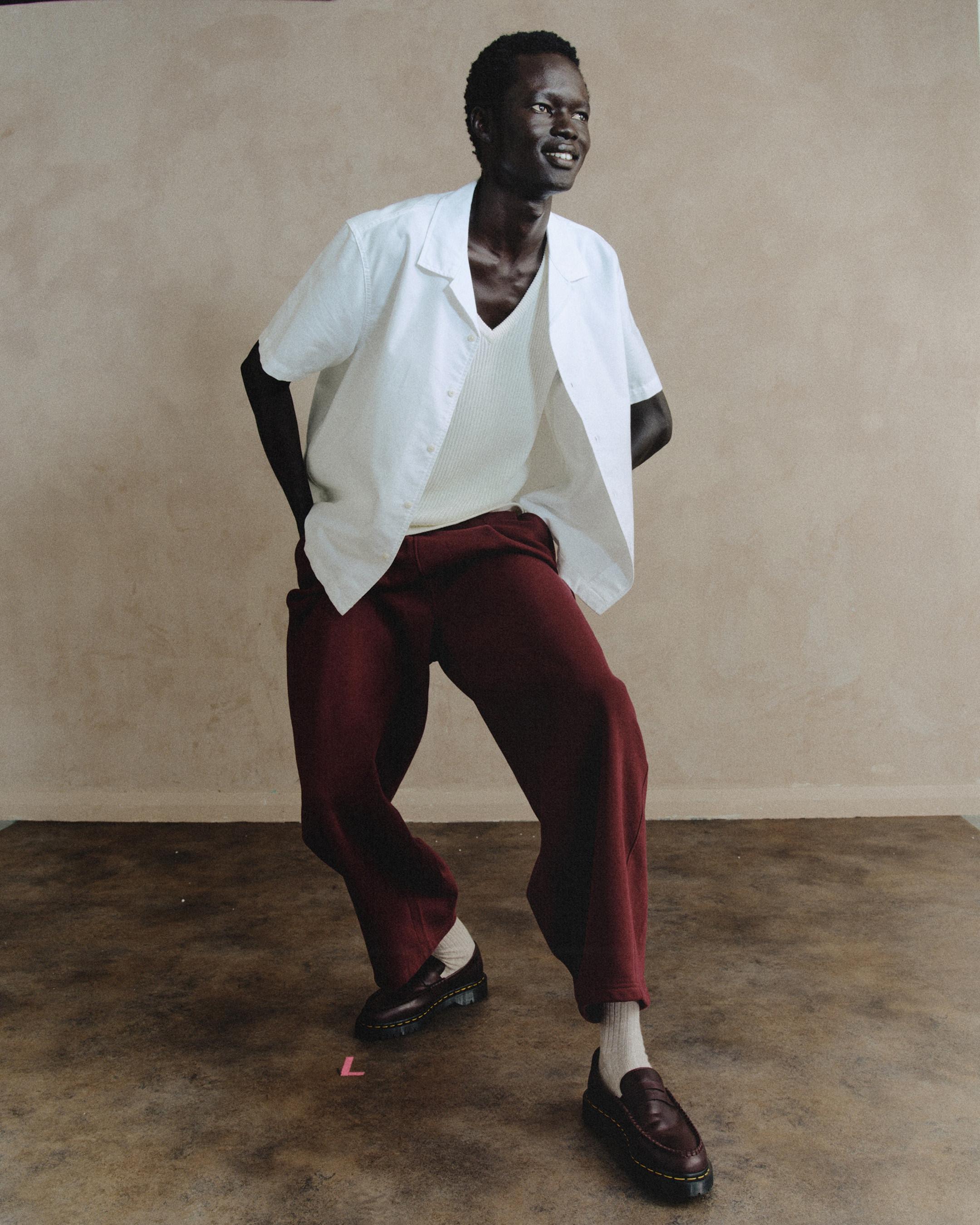Burgundy leather loafers with yellow welt stitching, worn with white socks and wide-leg trousers