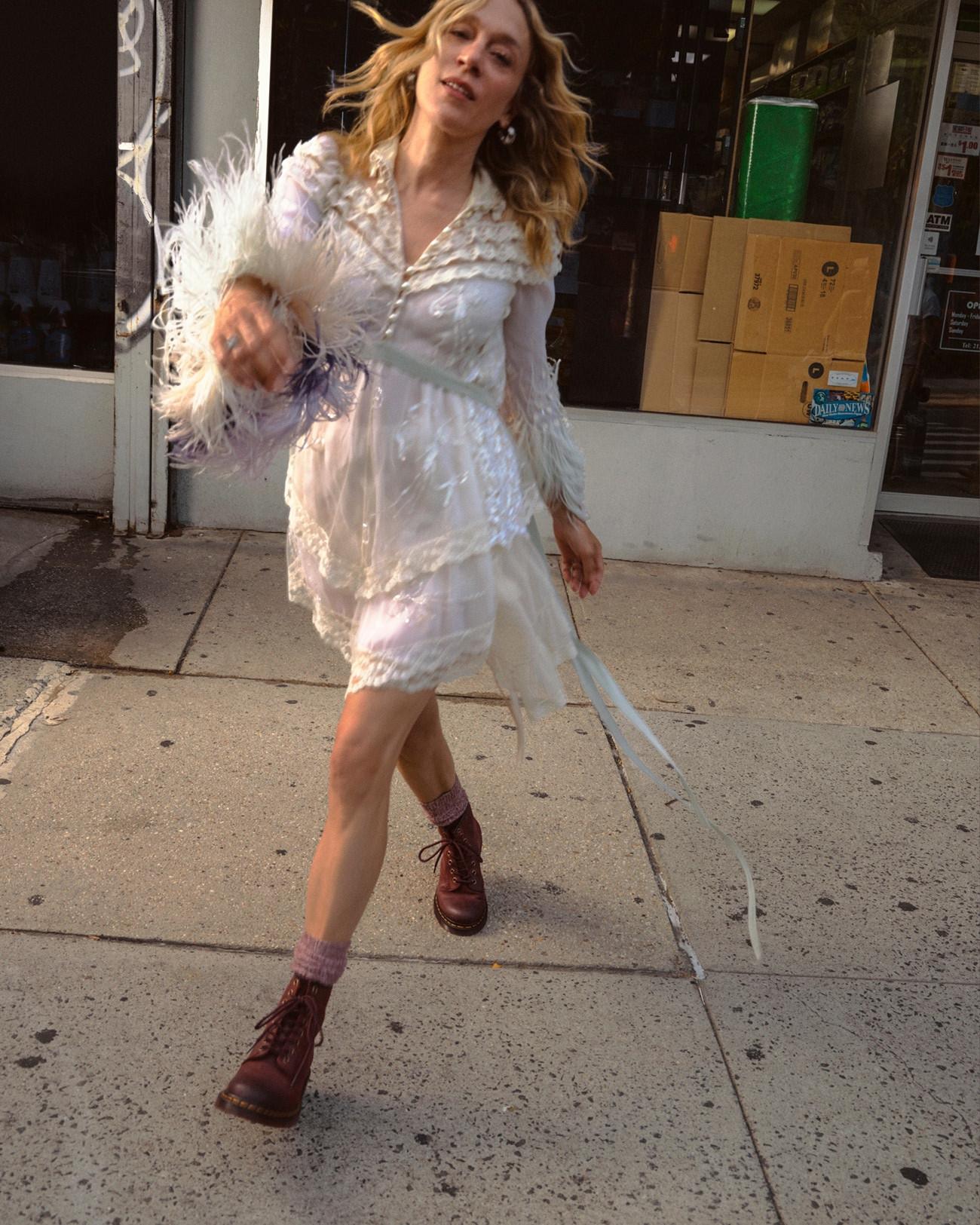 Burgundy leather lace-up boots with lilac socks, worn with a sheer white dress on a city pavement