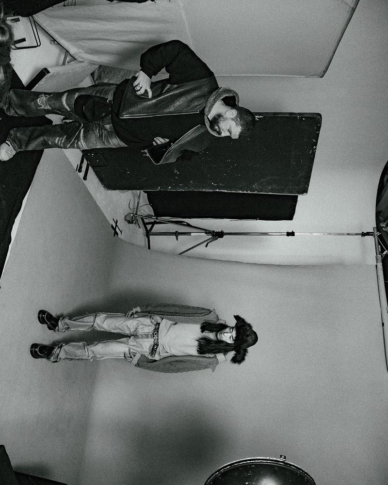 Two models in a studio wearing lace-up boots, relaxed denim and layered jackets