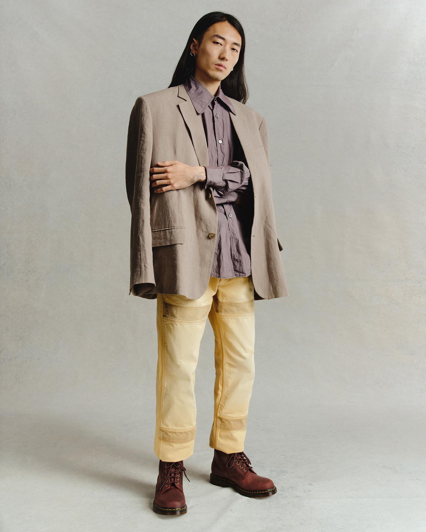 Persona con blazer beige y camisa malva, con botas burdeos de cordones