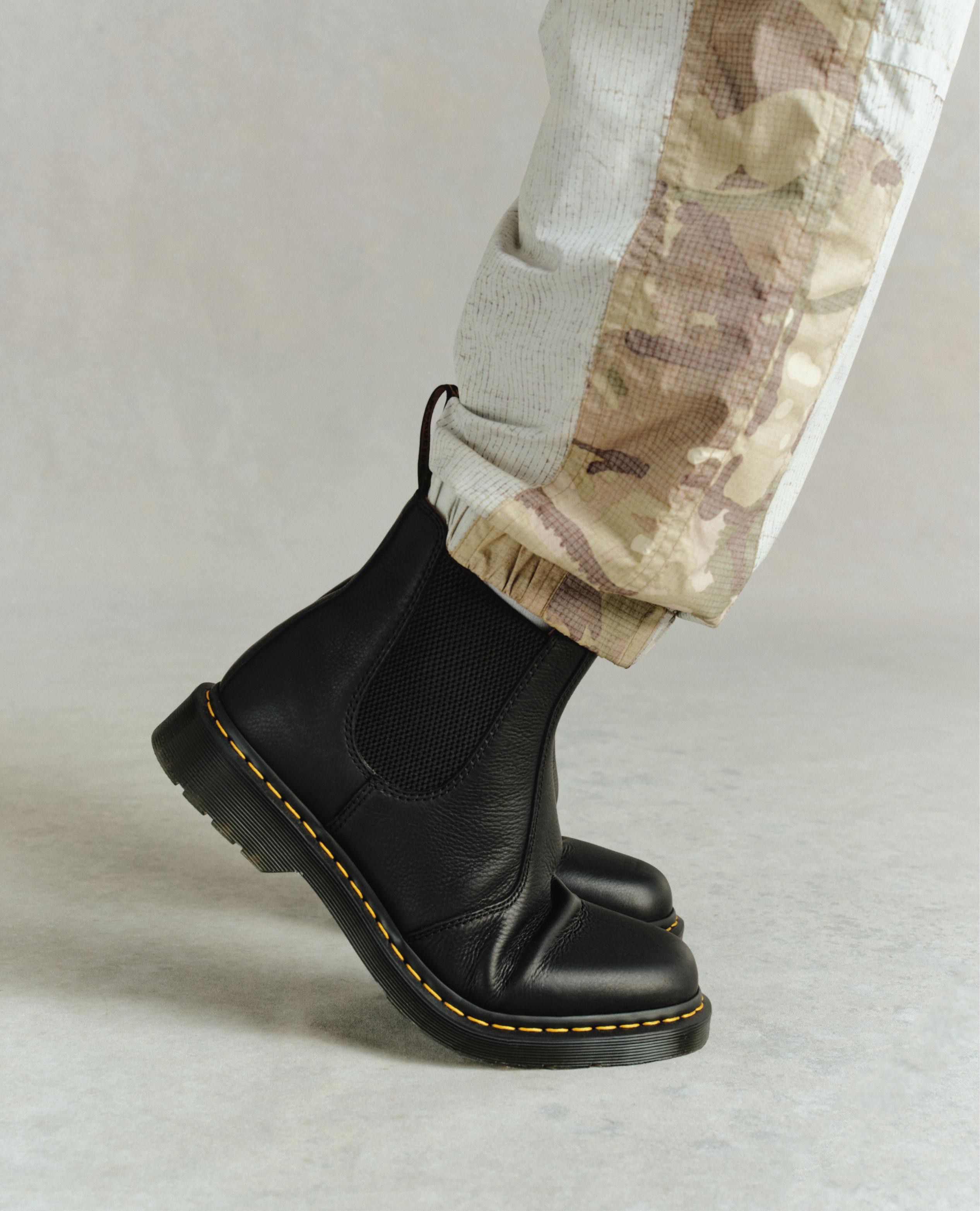 Botines Chelsea de piel negra con costura amarilla, con pantalón camuflaje remangado